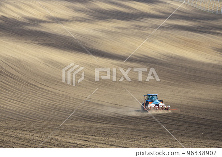 Tractor with seed drill in early spring landscape 96338902