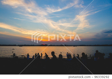 Silhouettes of people on river against backdrop of setting sun. Beautiful sunset on beach. Silhouettes of people on river against backdrop of setting sun. Beautiful sunset on beach. 96339292