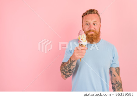 Hungry man with beard and tattoos eats a big icecream Hungry man with beard and tattoos eats a big icecream 96339595