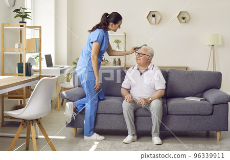 Friendly young female nurse combs hair of older man sitting on sofa in nursing home. Friendly young female nurse combs hair of older man sitting on sofa in nursing home. 96339911
