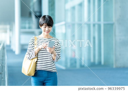 A young woman operating a smartphone. 96339975