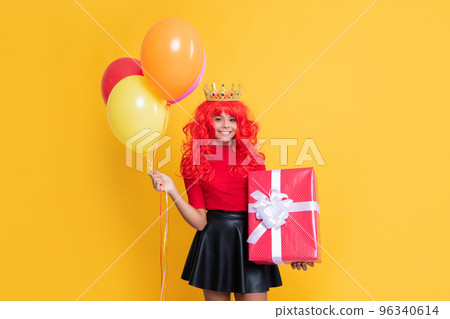 cheerful child in crown with present box and party balloon on yellow background cheerful child in crown with present box and party balloon on yellow background 96340614