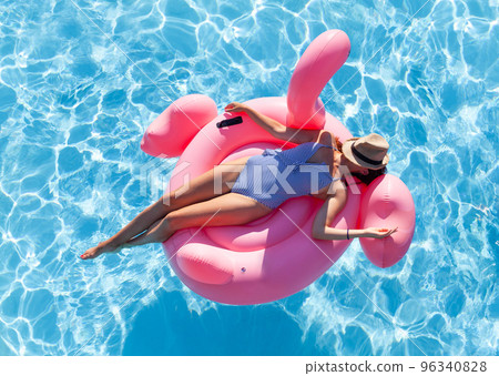 Woman relaxing on pink flamingo inflatable ring Woman relaxing on pink flamingo inflatable ring 96340828