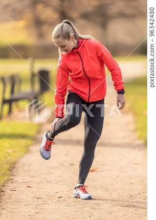 A young athlete sprained her calf while running, she holds it in pain A young athlete sprained her calf while running, she holds it in pain 96342480