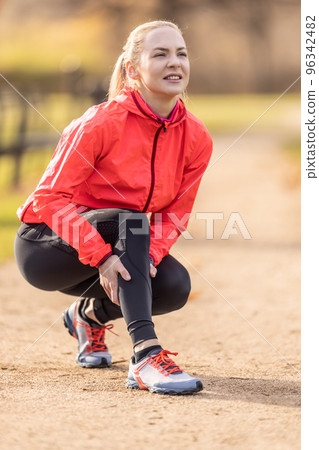 A young athlete sprained her calf while running, she holds it in pain A young athlete sprained her calf while running, she holds it in pain 96342482