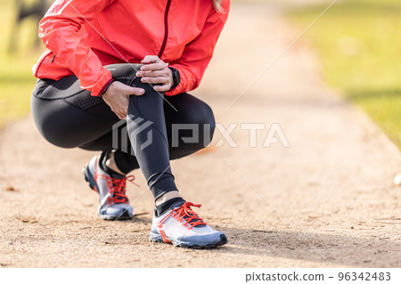 A young athlete sprained her knee while running, she holds it in pain 96342483