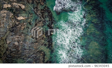 Waves break on the rocky shore of the Celtic Sea, top view. White foam on the waves. The coastline of the Atlantic. Turquoise water. Breathtaking seaside landscape. View from above. 96343045