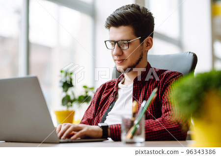 Young man working on laptop. Education and working online. Freelancer, technology, remote job. Young man working on laptop. Education and working online. Freelancer, technology, remote job. 96343386