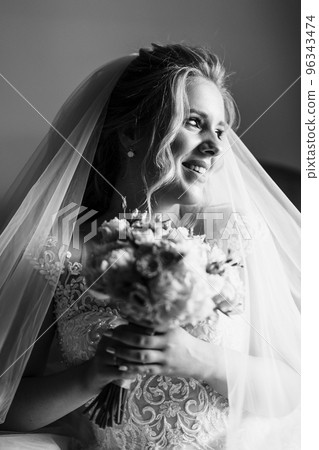Portrait of beautiful bride with fashion veil. A photo of delicate bride's hands hidden under a veil Portrait of beautiful bride with fashion veil. A photo of delicate bride's hands hidden under a veil 96343474