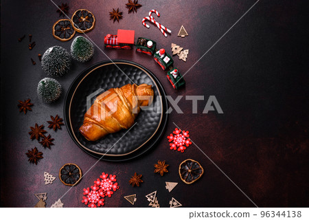 Beautiful different Christmas decorations and croissant on a brown concrete table Beautiful different Christmas decorations and croissant on a brown concrete table 96344138