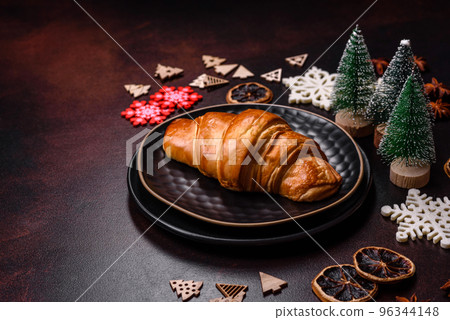 Beautiful different Christmas decorations and croissant on a brown concrete table Beautiful different Christmas decorations and croissant on a brown concrete table 96344148