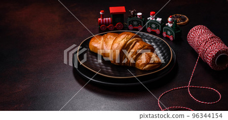 Beautiful different Christmas decorations and croissant on a brown concrete table Beautiful different Christmas decorations and croissant on a brown concrete table 96344154