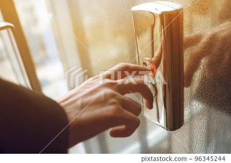 Man pressing elevator button. finger presses the elevator button. Red button. sunset light. Man pressing elevator button. finger presses the elevator button. Red button. sunset light. 96345244