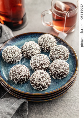 Coconut chocolate balls on plate on kitchen table. 96345952