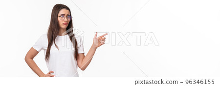 Waist-up portrait of uneasy, sad and gloomy young brunette woman in glasses, looking and pointing finger right with sulking unhappy face, express jealousy or regret, grieving white background Waist-up portrait of uneasy, sad and gloomy young brunette woman in glasses, looking and pointing finger right with sulking unhappy face, express jealousy or regret, grieving white background 96346155