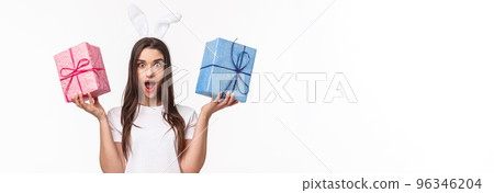 Celebration, holidays and presents concept. Portrait of charismatic young woman in lovely rabbit ears, shaking two gift box and look camera with opened mouth and surprised expression, receive present Celebration, holidays and presents concept. Portrait of charismatic young woman in lovely rabbit ears, shaking two gift box and look camera with opened mouth and surprised expression, receive present 96346204