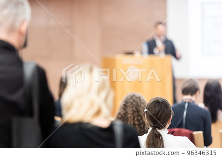 Speaker giving a talk in conference hall at business event. Rear view of unrecognizable people in audience at the conference hall. Business and entrepreneurship concept 96346315