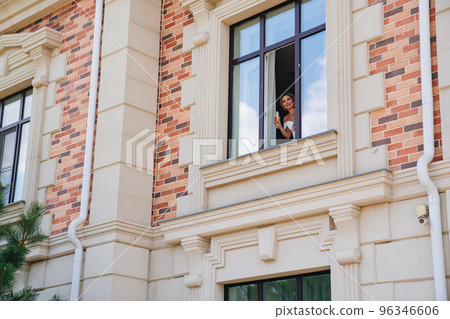 a happy bride with a glass of champagne waits for the groom at the window a happy bride with a glass of champagne waits for the groom at the window 96346606