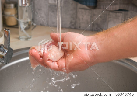 A man washes defrosted raw chicken fillet. Fresh 96346740