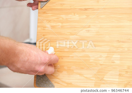 A man wipes a bamboo cutting board with a white A man wipes a bamboo cutting board with a white 96346744