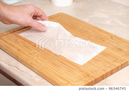 A man wipes a bamboo cutting board with a white A man wipes a bamboo cutting board with a white 96346745