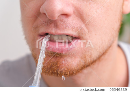 A handsome man cleans his mouth and teeth with a 96346889