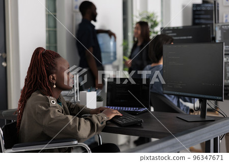 Programmer in wheelchiar typing html code on computer, working with cloud computing terminal window. Disabled software developer writing artificial intelligence algorithm in it company office. Programmer in wheelchiar typing html code on computer, working with cloud computing terminal window. Disabled software developer writing artificial intelligence algorithm in it company office. 96347671