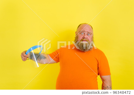 Doubter man with beard and tattoos is worried about a protective face shield against covid-19 96348472