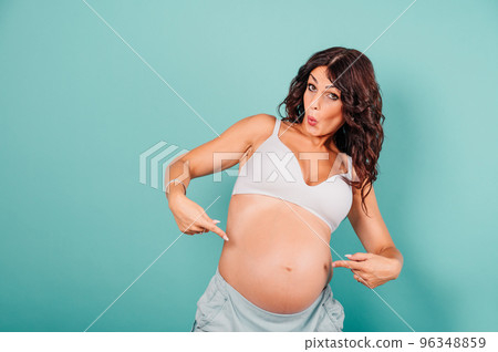 Pregnant amazed woman expecting a child caresses her belly 96348859