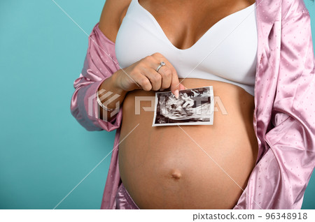 Pregnant mom shows an ultrasound of her son 96348918
