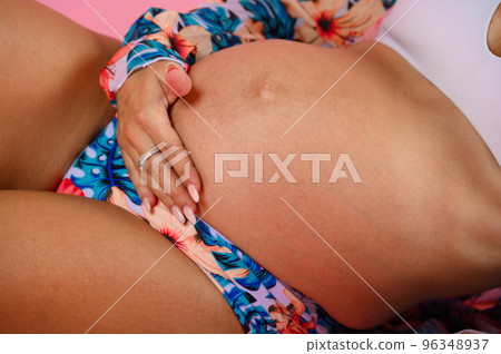 Pregnant woman expecting a child caresses her belly 96348937