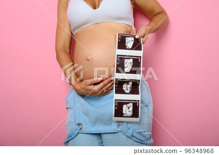 Pregnant mom shows an ultrasound of her son 96348968