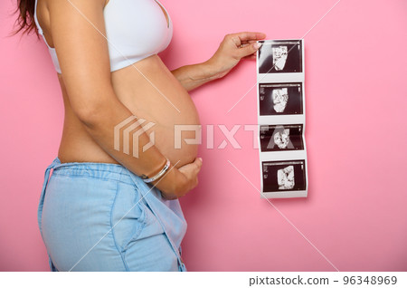 Pregnant mom shows an ultrasound of her son 96348969