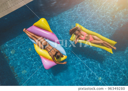 Friends in swimsuit in the pool getting a tan 96349280