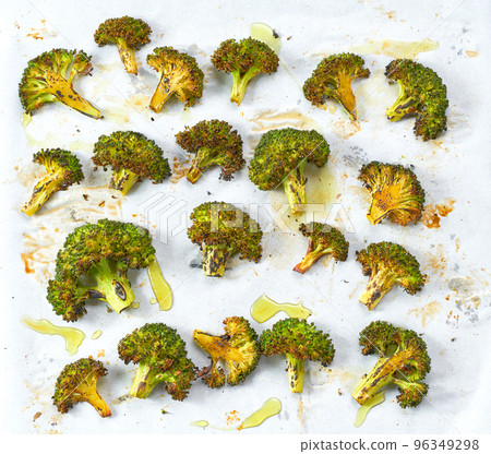 Baked broccoli with olive oil and spices on parchment paper, close up. Baked broccoli with olive oil and spices on parchment paper, close up. 96349298