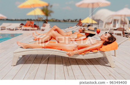 Group of friends in swimsuit drink a cocktail in a swimming pool Group of friends in swimsuit drink a cocktail in a swimming pool 96349400