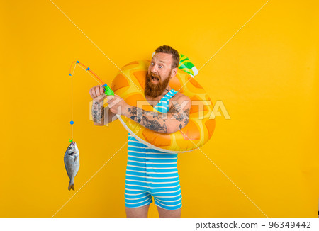 Man with beard and inflatable donut catches fish 96349442