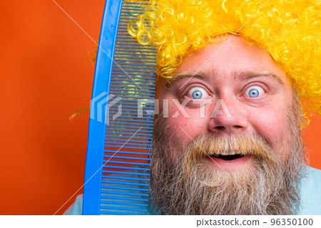 Fat amazed man with beard, tattoos and sunglasses combs himself with a giant comb Fat amazed man with beard, tattoos and sunglasses combs himself with a giant comb 96350100
