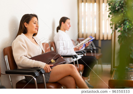 Positive woman sitting at hall at office 96350333