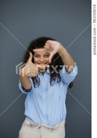 Smiling attractive young business woman in blue shirt posing on gray background Smiling attractive young business woman in blue shirt posing on gray background 96350659