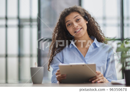 Brunette business woman using headset to communicate and advise people in customer service office. 96350678