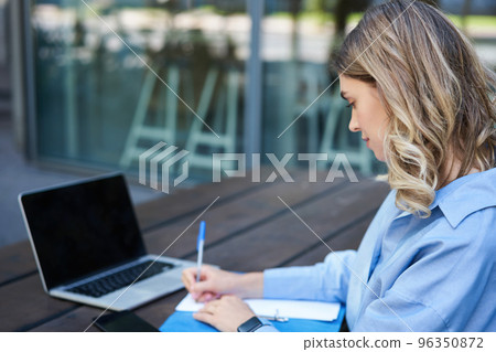 Close up portrait of woman student attend online course classes, sitting outside on fresh air with laptop and taking notes. Businesswoman video chat on computer Close up portrait of woman student attend online course classes, sitting outside on fresh air with laptop and taking notes. Businesswoman video chat on computer 96350872