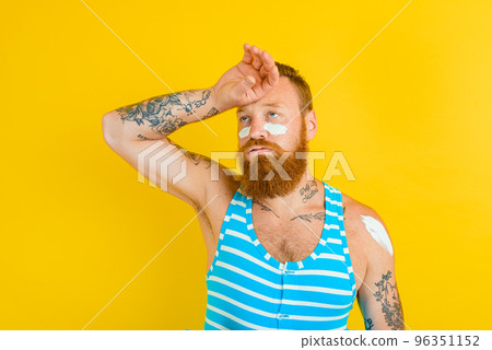 man with tattoos and swimsuit puts on sunscreen man with tattoos and swimsuit puts on sunscreen 96351152
