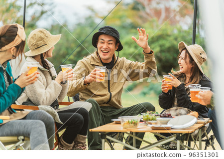 A popular Asian man who jokes and cheers up while drinking beer with his friends at a campsite in autumn and winter 96351301