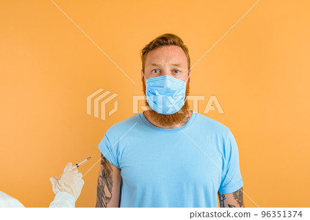 Serious man with beard, tattoo and mask for covid-19 is ready for the virus vaccine 96351374