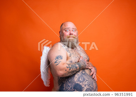 Fat afraid man with beard ,tattoos and wings acts like an angel Fat afraid man with beard ,tattoos and wings acts like an angel 96351991