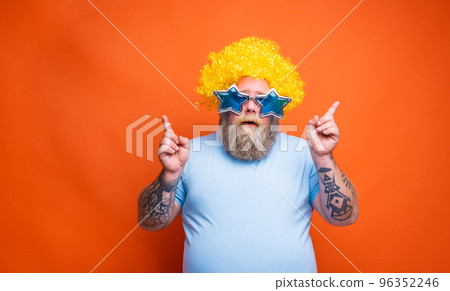 Fat thoughtful man with beard, tattoos and sunglasses dances music on a disco Fat thoughtful man with beard, tattoos and sunglasses dances music on a disco 96352246