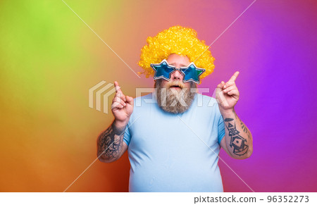Fat thoughtful man with beard, tattoos and sunglasses dances music on a disco Fat thoughtful man with beard, tattoos and sunglasses dances music on a disco 96352273