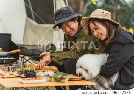 Couple campers cooking with their dog at the autumn/winter campsite Couple campers cooking with their dog at the autumn/winter campsite 96352526
