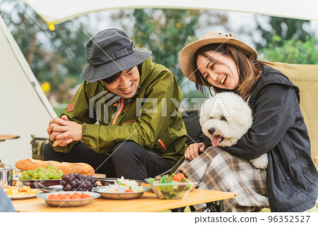 Couple campers cooking with their dog at the autumn/winter campsite Couple campers cooking with their dog at the autumn/winter campsite 96352527